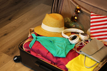 Collected suitcase for travel. Suitcase in open view closeup with things to rest on a wooden background