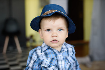 sad smiling little child boy in a blue hat