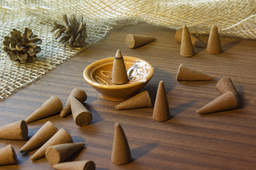 Incense aroma cones in a stand on a wooden table. Aromatherapy theme background.