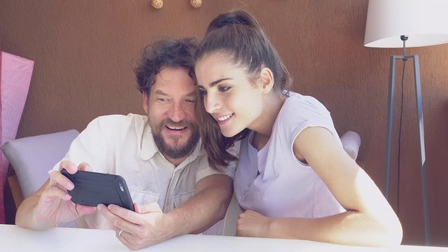 Happy couple laughing looking pictures on cell phone 4K slow motion