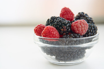 low angle shot berries in transparent bowl on a white kitchen table