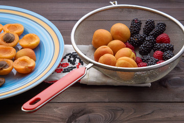 colander with the washed-up berries raspberry and blackberry and apricots