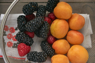 macro colander with red raspberries, black blackberries and orange apricots