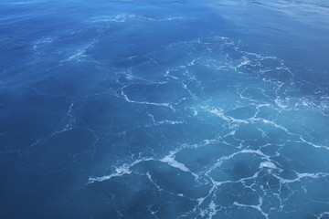 Aqua blue seaside with ship tail photo background. Clean blue sea water closeup.