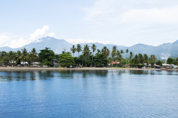 Seaside landscape with still blue water and tropical island. Sea view with distant island
