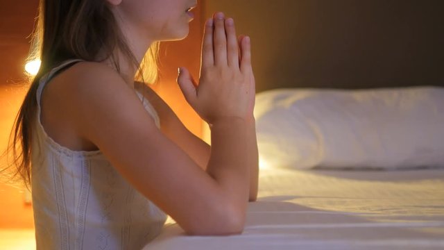The child prays. A little girl says a prayer before going to sleep. The girl makes a wish.