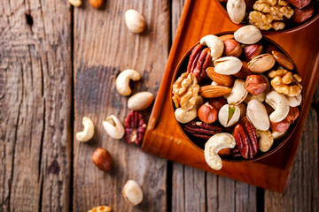Nuts Mixed in a wooden plate.Assortment, Walnuts,Pecan,Almonds,Hazelnuts,Cashews,Pistachios.Concept of Healthy Eating.Vegetarian.Copy space.selective focus.