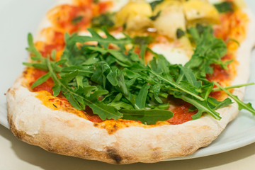 Fresh baked pizza with melted cheese, Italian herbs and tomato sauce and fresh basil on a white plate. Italian food, menu, restaurant concept