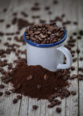 Cup of porcelain with coffee beans in foreground in vintage style.