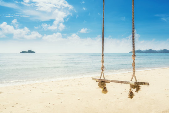 Wooden swing chair hanging on tree near beach at island in Phuket, Thailand. Summer Vacation Travel and Holiday concept.
