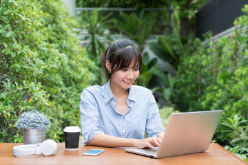 Asian woman in smiling face using laptop, workplace in tree garden. Concept of Asian woman lifestyle.