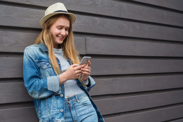 teen woman smartphone outside wood wall