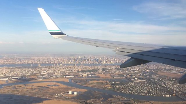 Looking trough window of an aircraft, airplane or plane wing. View from plane window during landing or takeoff over the city urban area