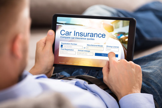 Man Filling Car Insurance Form On Digital Tablet