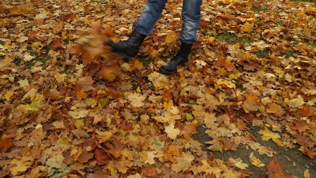 Male legs kicking autumn fall leaves. Guy having fun in park forest. 4K ProRes HQ codec.