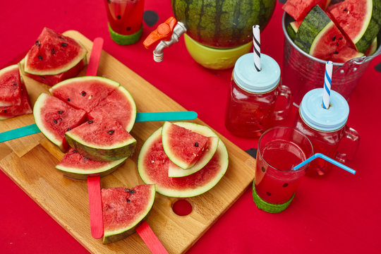 Close up summer outdoor table with red sheet and watermelon style drinks and slices for watermelon party