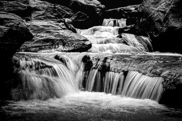 small waterfall among rocks in black and white
