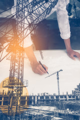 Double exposure of  architect working on blueprint with construction site.