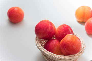 White background. Plums in a basket.