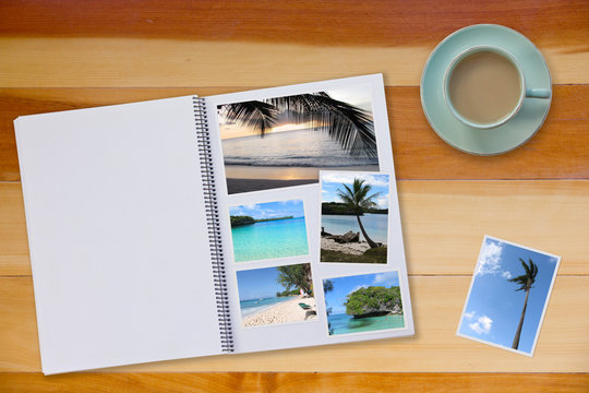 Photobook Album  with Travel Photo on Wooden Floor Table with Travel Photos and Coffee or Tea in Cup
