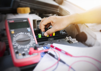 Fototapeta na wymiar Close up of auto mechanic jumping battery car,check voltage level car battery.