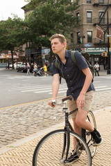 Fototapeta premium Portrait of young caucasian teenager riding bike on city street