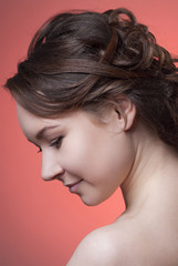 The portrait in profile of brown-haired women with the hair of a Greek braid and clean skin isolated on light pink background. Close-up. Makeup Nude.