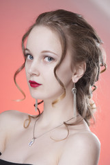 Close-up portrait of brown-haired girl with clean skin and hair Greek braid. Isolated pink background.