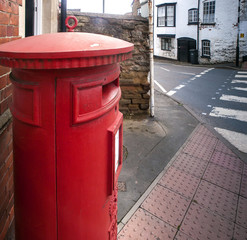 Fototapeta na wymiar A classic British red postbox near a zebra crossing in a village in Herefordshire, UK