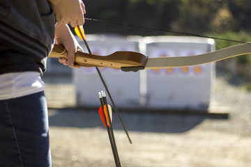 Archery or shooting range with bow and arrows on a sunny outdoor setting.  The equipment is used in...
