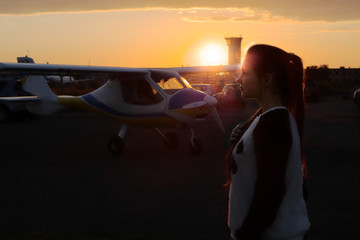 Girl standing on an aerodrome on the background of the sunset