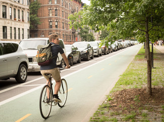 Back view of modern hipster man riding bike on bike lane in the city