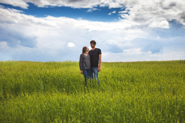 Young couple walking through green field