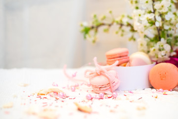 Tender pastel pink and orande macaroons on a white blanket and background