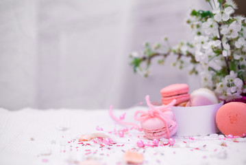 Tender pastel pink and orande macaroons on a white blanket and background