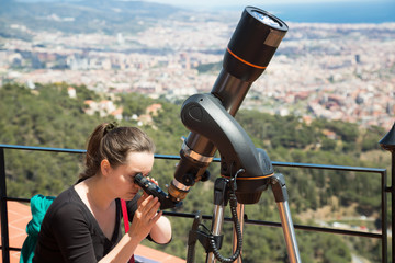 Woman tourist looking in telescope on roof