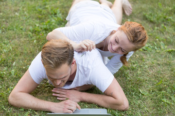 Fototapeta na wymiar Young couple relaxing using computer laptop in park