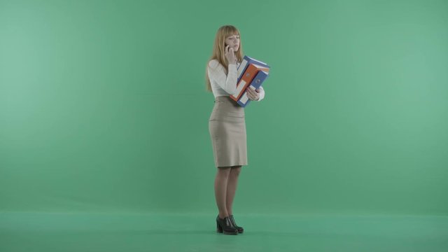 a redhead woman talks on the phone standing with binders