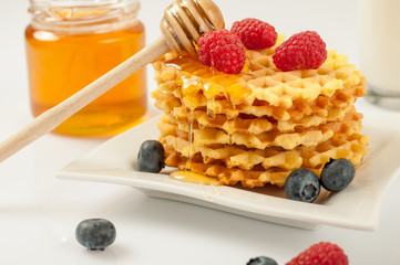 Homemade waffles with berries in plate on grey table