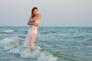 Fototapeta na wymiar Sexy girl on the beach. Sexy girl in the ocean waves. fashion portrait women on the sea. beautiful girl in a wet white dress. Girl in the sea 
