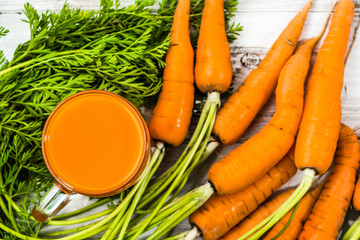 Carrot juice and fresh carrots on wooden background, overhead