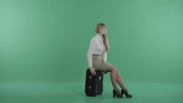 a bored girl is sitting on a luggage waiting