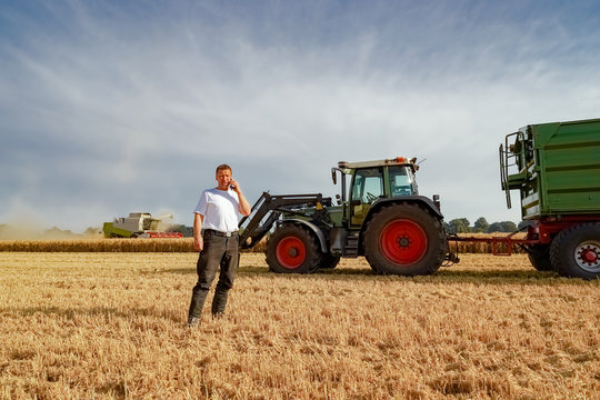 Getreideernte - Landwirt telefoniert vor Landtechnik