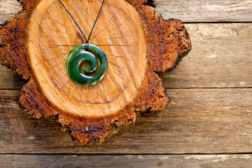 Maori New Zealand Greenstone pounamu jade Koru (spiral fern) shape pendant on cross section of timber log