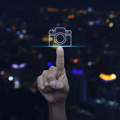 Hand pressing camera flat icon over blur colourful night light city tower, Business camera service concept