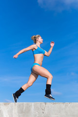 Young woman in sportswear running along seafront