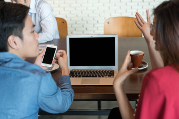 Laptop with blank screen on table with two coworker discuss to each other