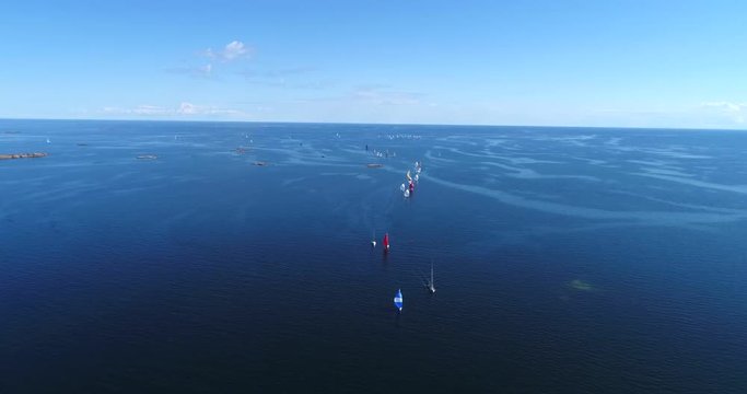 Sailboat regatta, Cinema 4k aerial decreasing tilt view of a lot of sailboats in the baltic sea and heading towards hanko city, out on the  finnish archipelago, turquoise sea, on hango regatta day