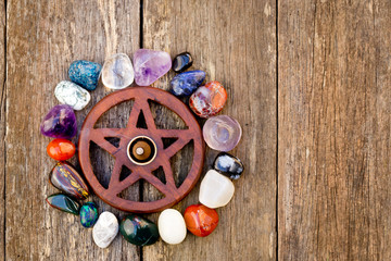 Wooden wiccan pentagram with incense burning surrounded by crystals - on wooden background
