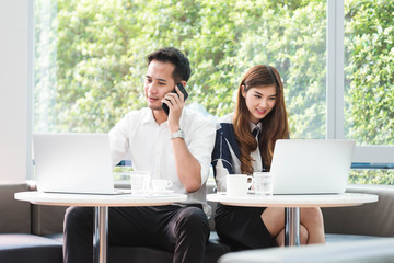 Two asian coworkers use laptop work together